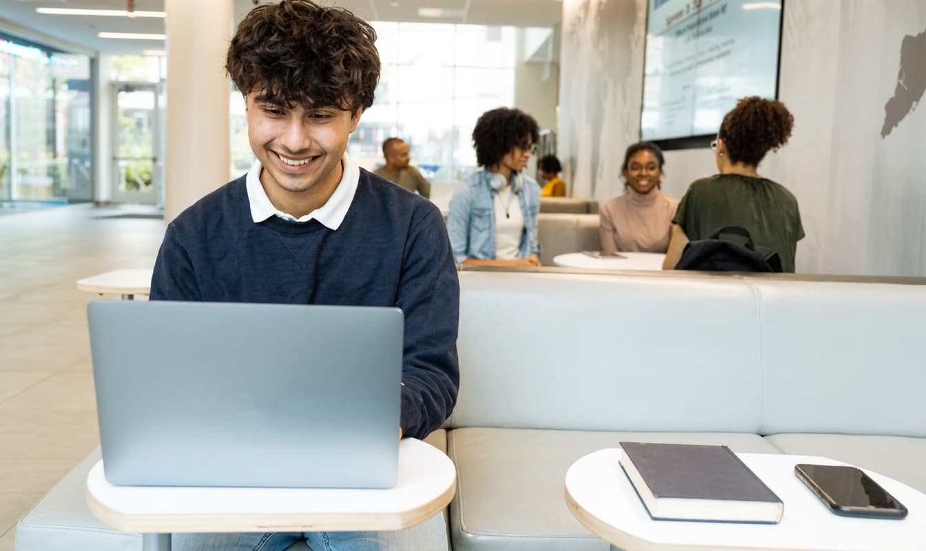 A student comparing study abroad options on a laptop in a campus lounge.