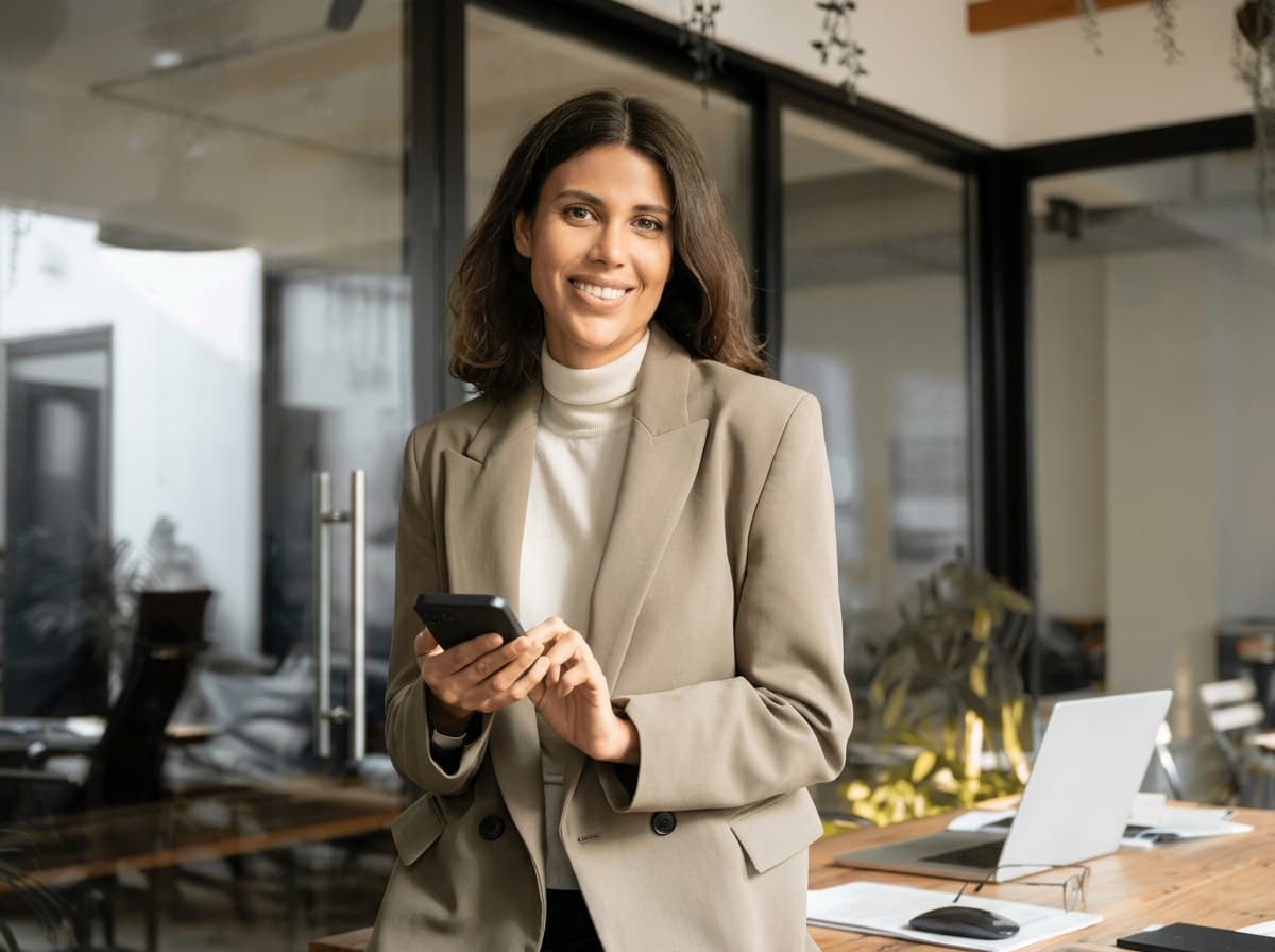 A young professional standing in a glass-walled open-plan office.