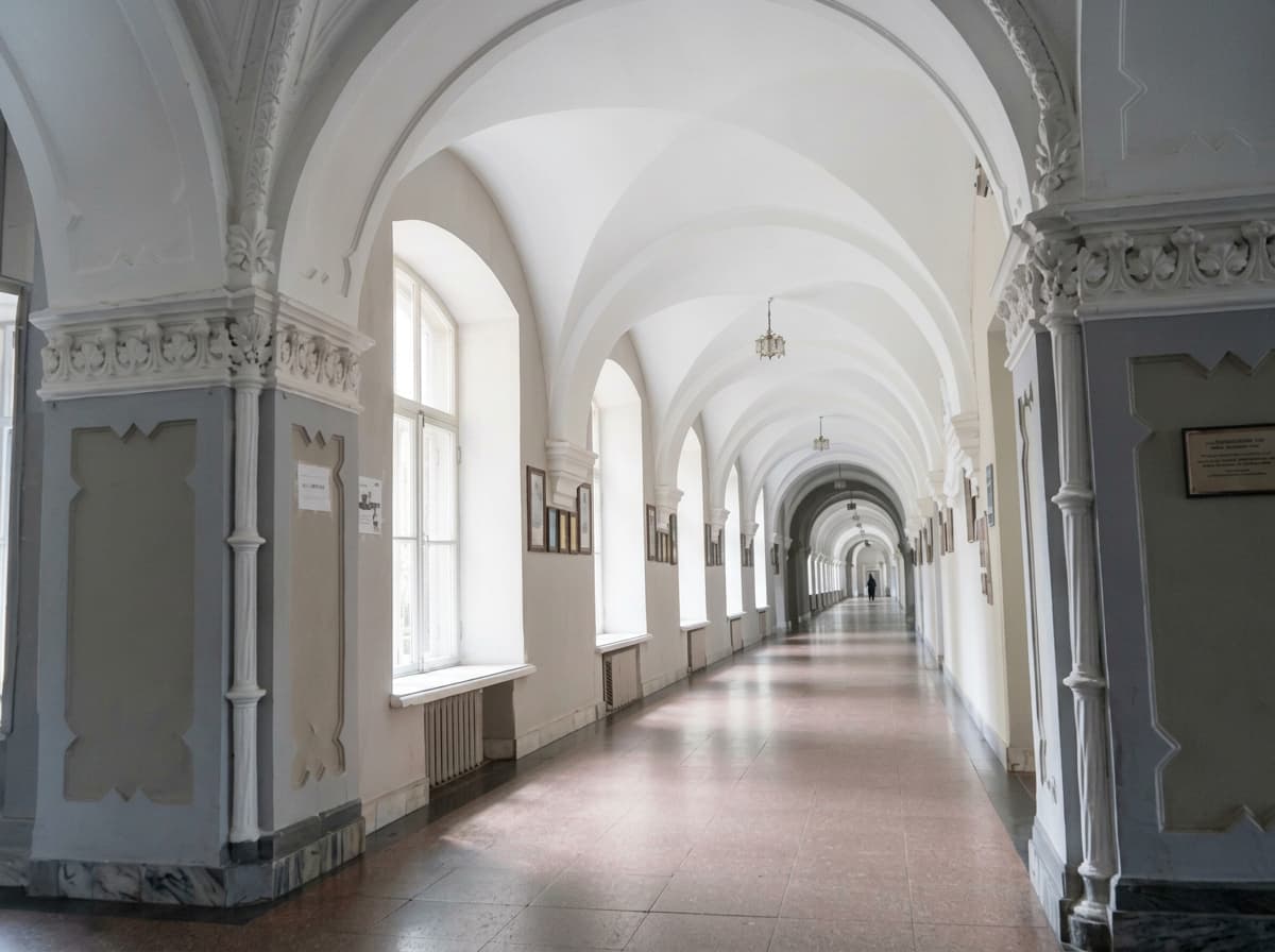 A long white vaulted corridor lined with tall arched windows.