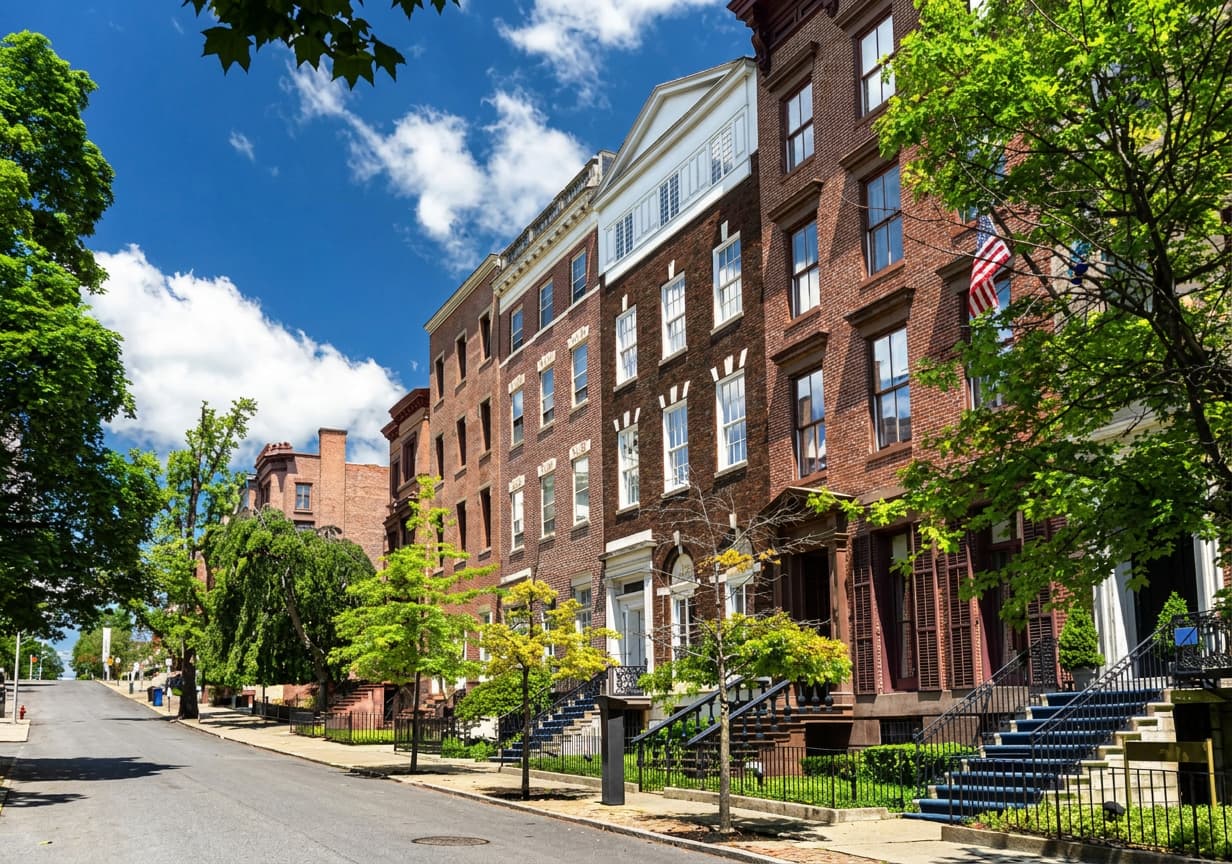 A tree-lined street of classic red-brick townhouses in the United States.