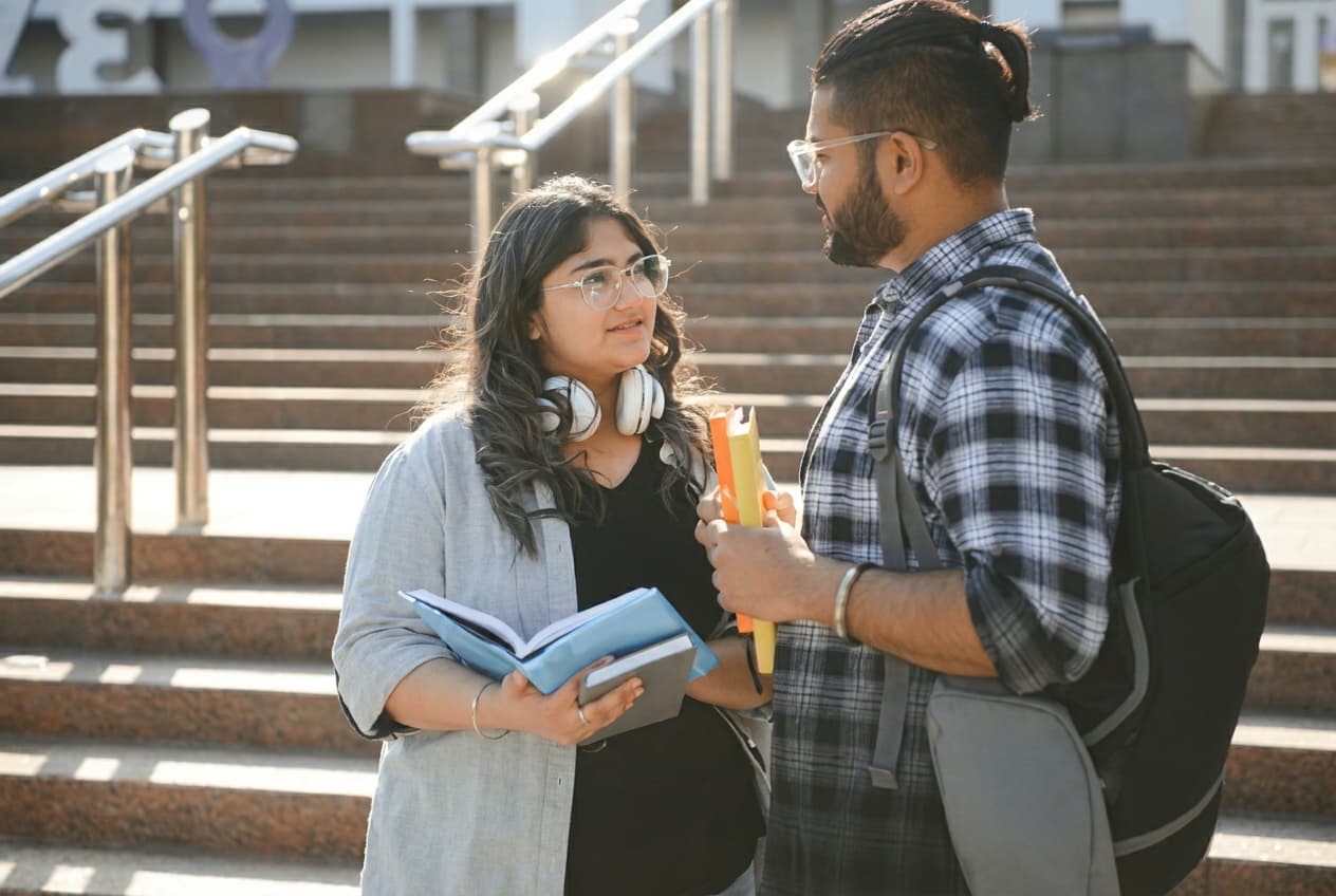 Two students talking one to one on campus steps.