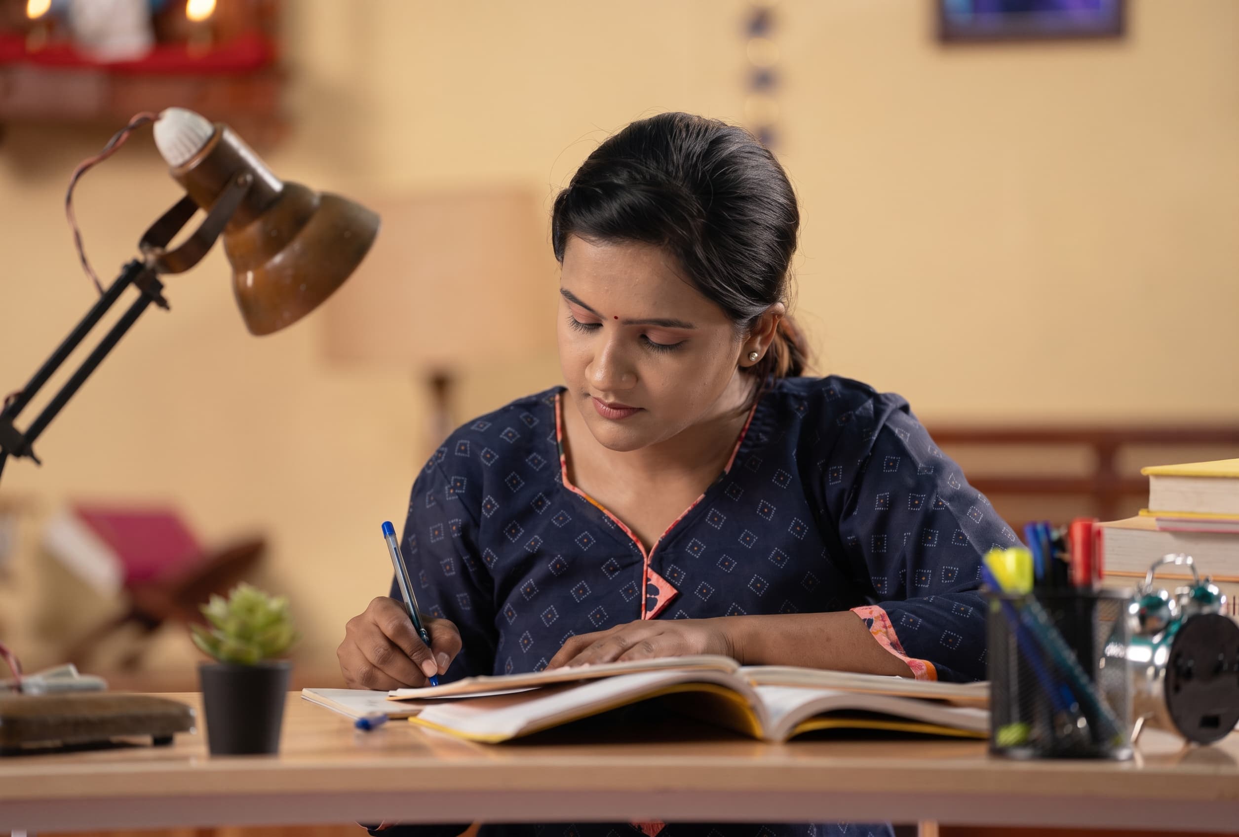 A student drafting a statement of purpose at a lamp-lit desk.