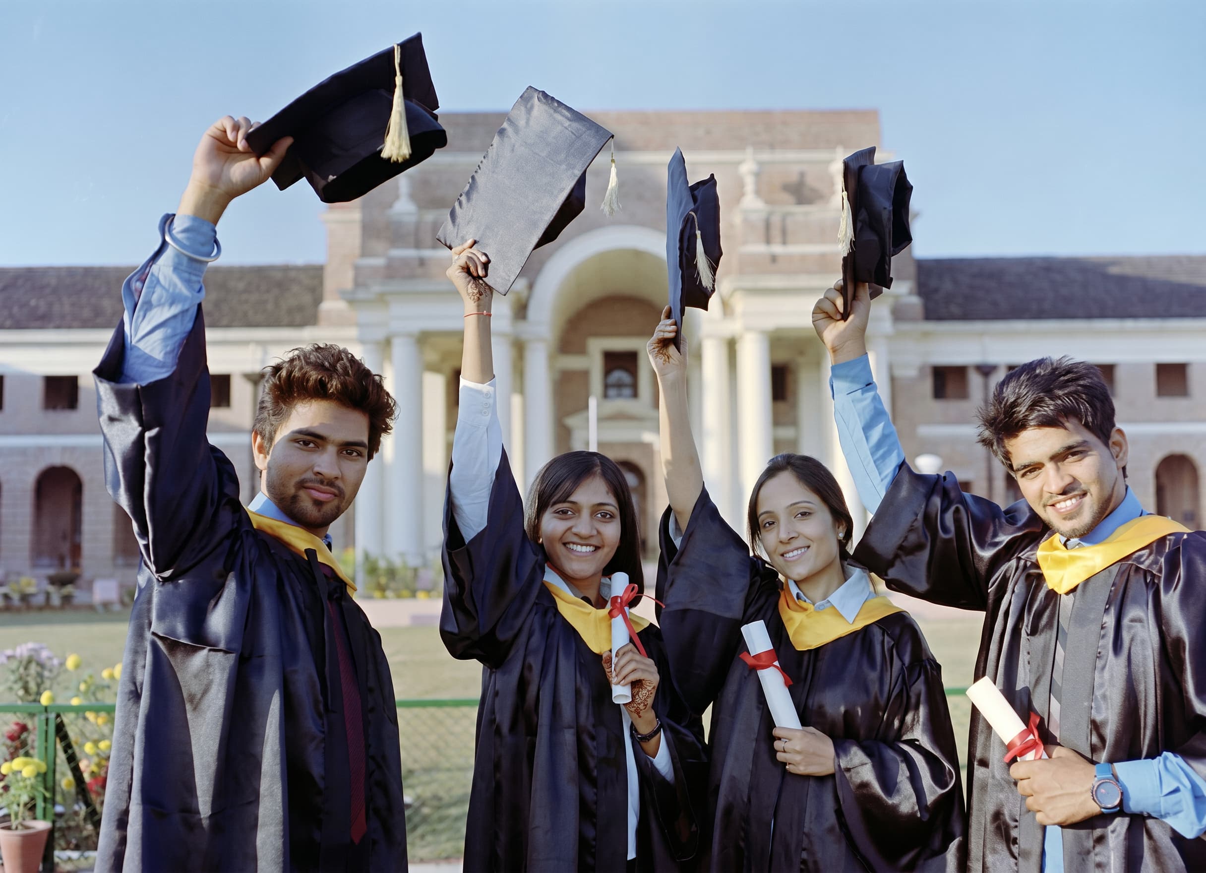 Graduates in caps and gowns celebrating with their diplomas.