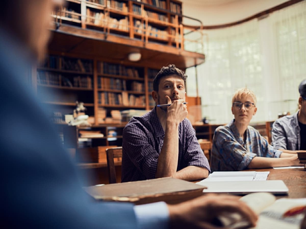 A student thinking through a research question in a reading room.