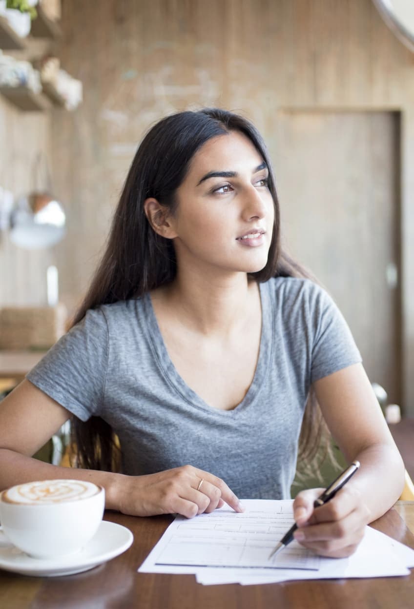 A student filling out an application form at a cafe table.