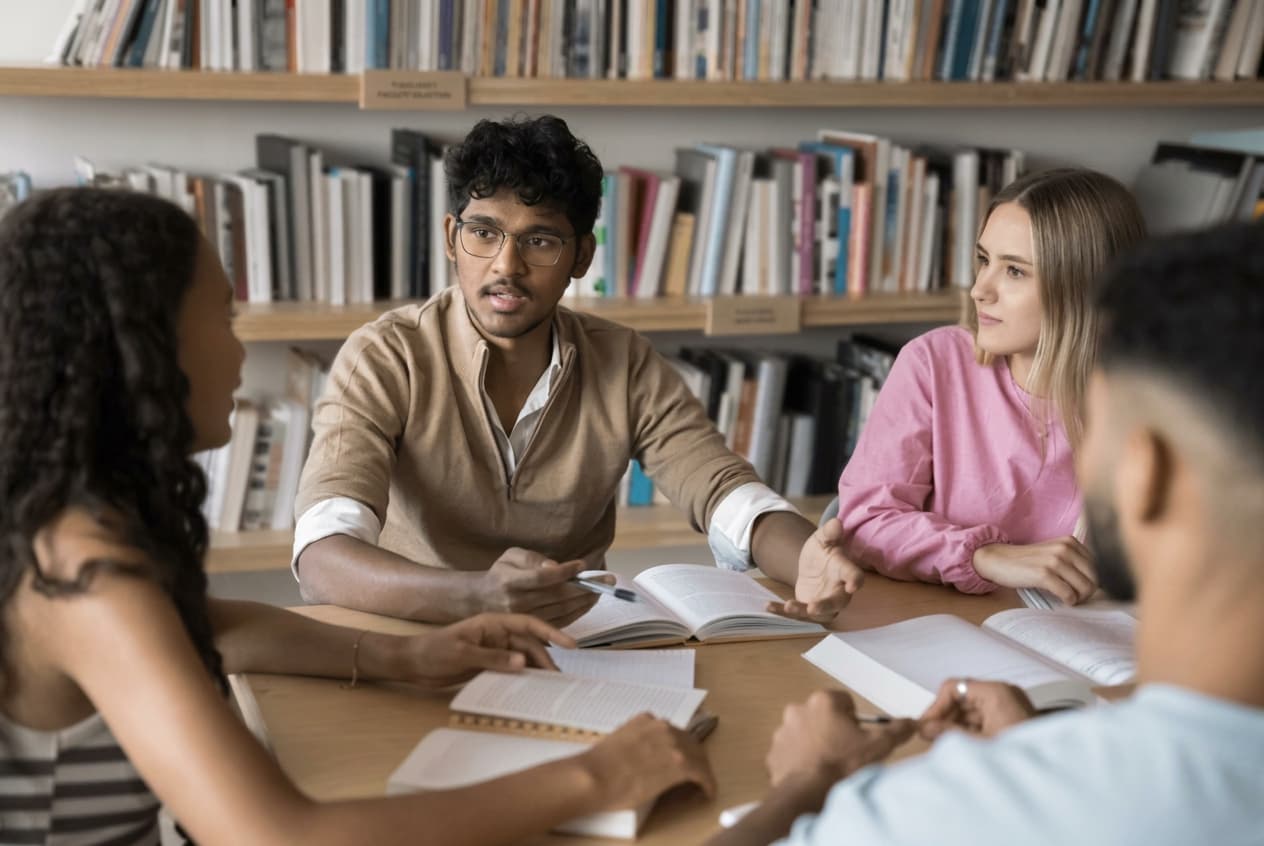 Students working through course material around a library table.