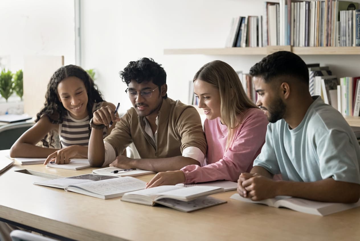 A small group of students planning together at a library table.
